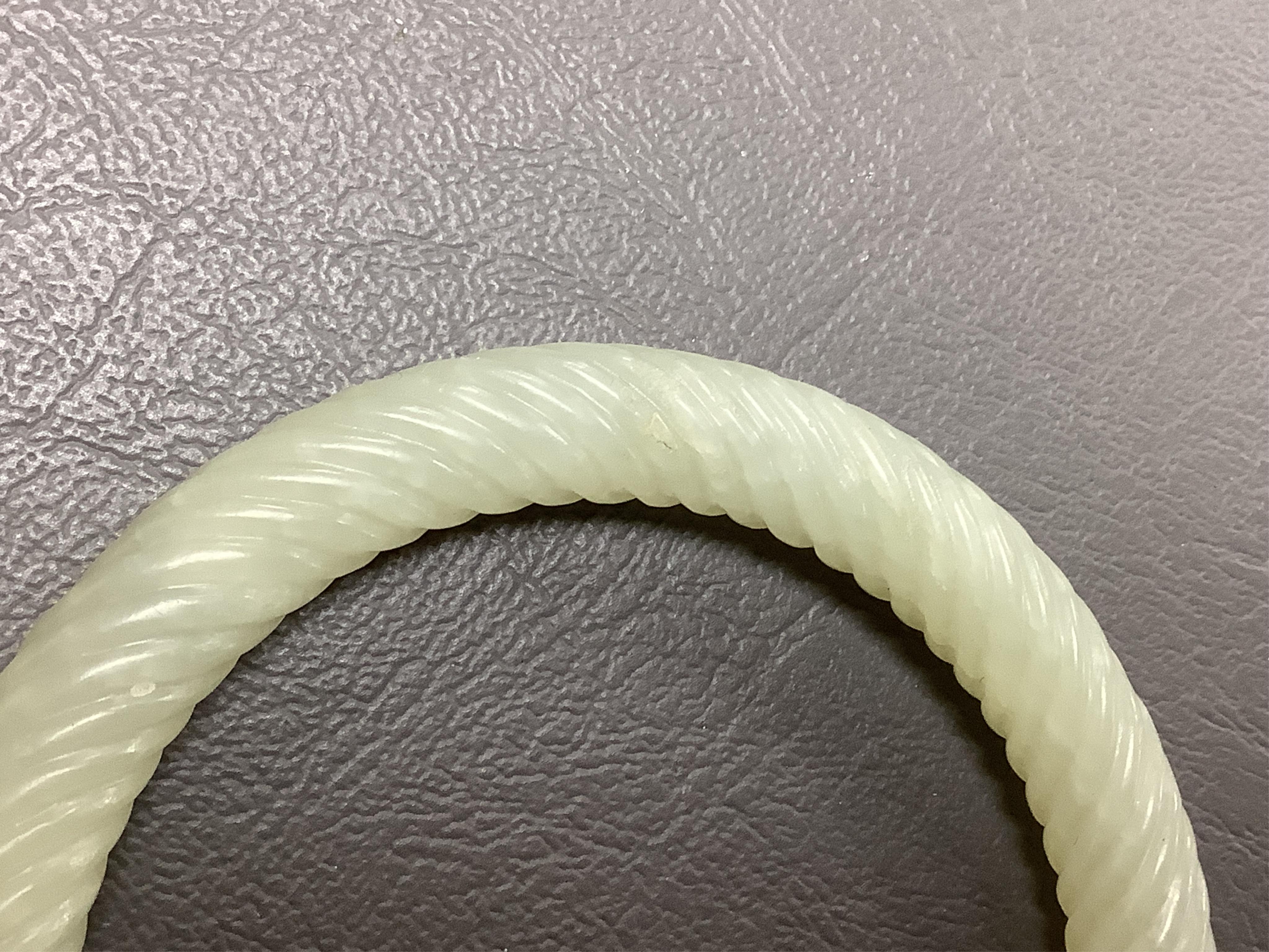 A Chinese pale celadon jade rope twist carved bangle, 8cm diameter